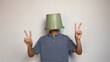 young man using a bucket on his head on a white background. showing a peaceful gesture.