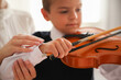 © New Africa - Young woman teaching little boy to play violin indoors, focus on hands