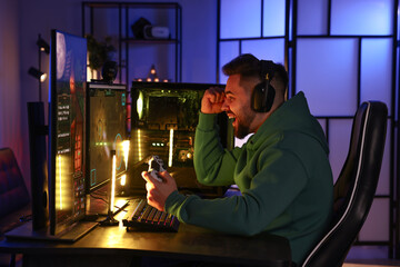 Canvas Print - Man playing video games with controller at table indoors