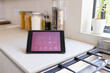 A tablet displaying smart home interface rests on a kitchen counter at home
