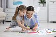 © New Africa - Mother and her little daughter drawing with colorful markers on floor at home