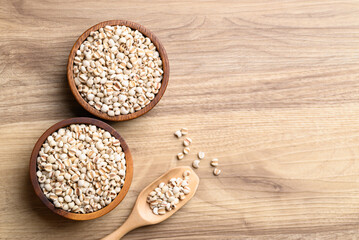 Wall Mural - Dried Job's tears or adlay millet in wooden bowl on wooden background, Table top view