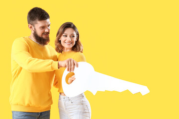 Canvas Print - Happy couple in love with paper key on yellow background