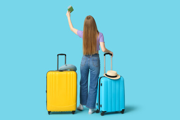 Sticker - Young woman with suitcases, raising up her hand with passport on blue background. Travel concept. Back view