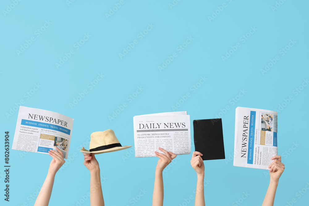 Female hands with newspapers, hat and notebook on color background
