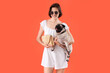 Young woman with cute pug dog and handbag on orange background