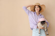 Young woman and cute pug dog in hats on beige background