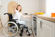 Young woman in wheelchair with brush painting drawer at home