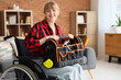 Young woman in wheelchair with tool bag at home