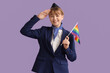 Young stewardess with LGBT flag on lilac background