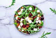 Sweet beetroot salad with feta cheese, fresh arugula, raisins and nuts, marble table background, top view