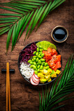 Fototapeta Na sufit - Poke bowl for balanced diet with salmon, avocado, radish, cabbage, beans, sesame and rice, wooden table background, top view