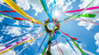 © woret - Colorful ribbons on maypole under blue sky with sun rays