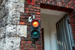 An old vintage pedestrian traffic light on the wall of a brick building.