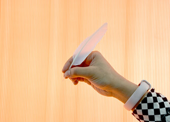 Closeup of Asian woman's Hand holding a white feather pen isolated on orange background Holding hands (writing) with a quill pen on a gray wall at Thailand.