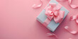 A pink gift box with a pink ribbon and sprinkles on a pink background.
