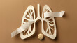 Paper lungs with white ribbon and tumors on brown background