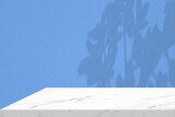 Fototapeta Mapy - White Marble Table Corner with Light Beam, Shadow, and Spotlight on the Blue Concrete Wall Background