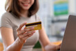 © Wasana - A woman is holding a credit card while sitting at a desk