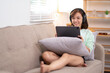 © Wasana - A woman is sitting on a couch with a tablet. Wearing headphones and enjoying her music.