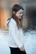 Smiling girl walks by the water in gentle evening light.