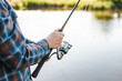 Man with fishing rod casting line into serene lake.
