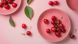 Plates and bowl with sweet cherries on pink background