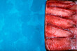 Beaked redfish or Sebastes mentella frozen in a row in a box on blue background. Mockup with copy space