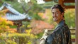 © tongpatong - Young, contented man wearing a kimono strolling and resting on a railing fence in a Japanese outdoor garden while taking in the scenery