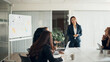 © Flamingo Images - CEO laughing while giving a whiteboard presentation to businesswomen in an office