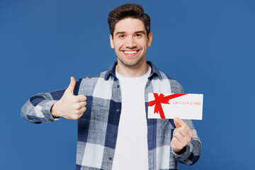 Wall Mural - Young amazed excited happy man he wear shirt white t-shirt casual clothes hold gift certificate coupon voucher card for store show thumb up isolated on plain blue cyan background. Lifestyle concept.