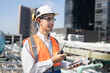 Portrait Asia male engineer in protective workwear is performing a conducts system check with use tablet computer and walkie talkie at rooftop building	