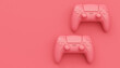 Video game joysticks or gamepads in plain monochrome pink color background
