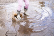 mischievous 5-year-old girl in rubber boots jumps with glee in puddle, closeup children's feet in splashes water, capturing pure and simple joys childhood and magic rainy day
