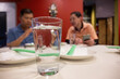 A glass of water on the table. Out-of-focus men talking and checking on smartphones.