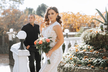 Wall Mural - A woman in a white dress is posing for a picture with a man. The man is wearing a black shirt. The woman is holding a bouquet of flowers