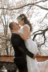 Wall Mural - A man and woman are embracing each other in a forest. The man is wearing a black shirt and the woman is wearing a white dress