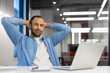 © Tetiana - Smiling and calm young American man relaxing in the office at the work table, sitting on the chair leaning back with closed eyes, holding his hands behind his head