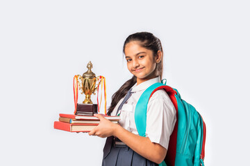 Excited Indian asian girl student in school uniform holding victory trophy in hand isolated on white background, Studio shot.