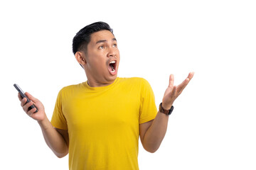 Wall Mural - Excited young Asian man holding mobile phone and looking up with shocked expression isolated on white background