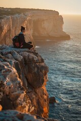 Poster - A person sitting on a cliff overlooking the ocean. Suitable for travel and relaxation concepts