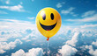 Yellow balloon with smiling emoticon face flying high up in the sky over the clouds.