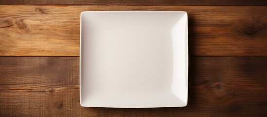 Poster - A copy space image of an empty square plate placed on a wooden surface offering ample space for your own creative design