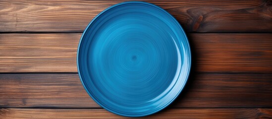 Poster - A blue plate rests on a wooden surface seen from above The wood s texture adds depth to the image leaving ample space for your creative design