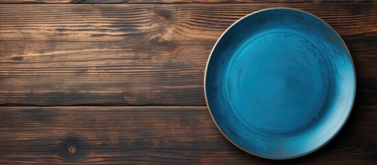 Poster - A blue plate rests on a wooden surface seen from above The wood s texture adds depth to the image leaving ample space for your creative design