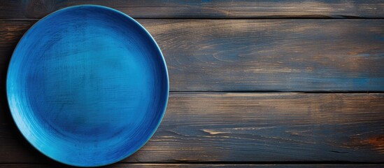 Poster - A blue plate rests on a wooden surface seen from above The wood s texture adds depth to the image leaving ample space for your creative design