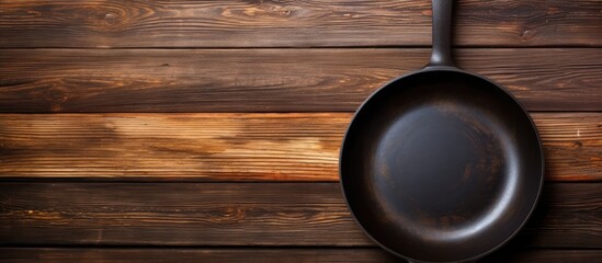 Poster - A cast iron frying pan with a non stick coating sits on a wooden table creating a captivating contrast against the rustic backdrop. with copy space image. Place for adding text or design