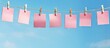 A copy space image of pink sticky notes attached to a rope hung against a blue background providing a place to write down reminders or to do lists