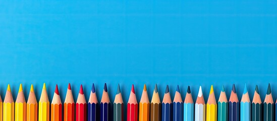 Poster - A colorful row of pencils against a blue backdrop with space for copy or images. with copy space image. Place for adding text or design