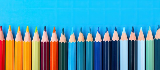 Poster - A colorful row of pencils against a blue backdrop with space for copy or images. with copy space image. Place for adding text or design